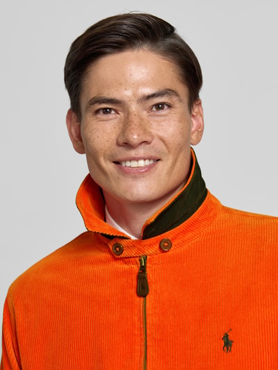 Männermodel trägt Regular Fit Blouson aus Baumwoll-Cord von Polo Ralph Lauren in leuchtendem Orange, Nahaufnahme Oberkörper.