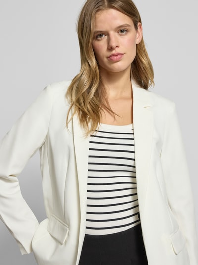 Kobiece modelka nosi Loose Fit Longblazer z wyhaftowanym logo Model 'BOZZY' od Pieces, efekt: jednolity kolor, długi rękaw, kieszenie z patką, kołnierz z połami, bez zapięcia, krój loose fit, zbliżenie na górną część sylwetki.