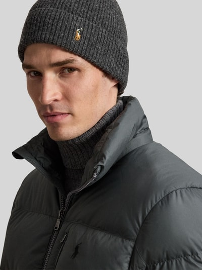 Männermodel trägt Regular Fit Daunenjacke mit Logo-Stitching von Polo Ralph Lauren, dunkle Farben, glatte Textur, Nahaufnahme Oberkörper. Herren Daunenjacke von Polo Ralph Lauren