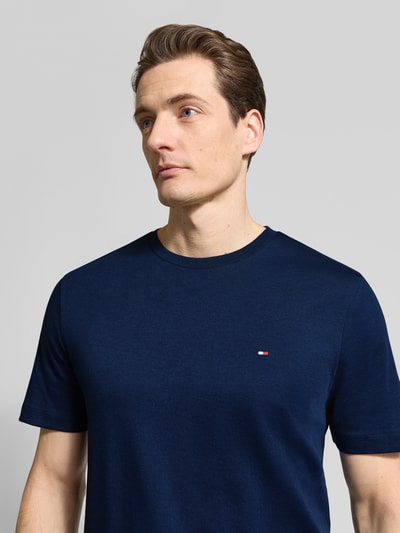 Männermodel trägt Regular Fit T-Shirt aus reiner Baumwolle von Tommy Hilfiger in Optik: Unifarben mit Logo-Detail, Nahaufnahme Oberkörper.
