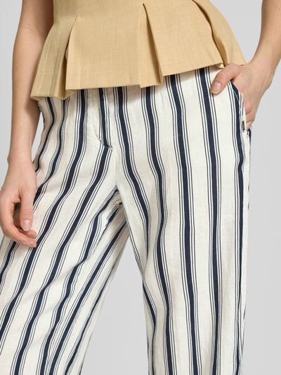 Frauenmodel trägt Straight Fit Leinenhose in verkürzter Passform von Christian Berg Woman, creme mit blauen Streifen, Reine Leinen, Knopf- und Reißverschluss, strukturierte Stofftextur, Bundweite bei Größe 36: 39 cm, Innenbeinlänge bei Größe 36: 66 cm, Nahaufnahme Oberkörper.