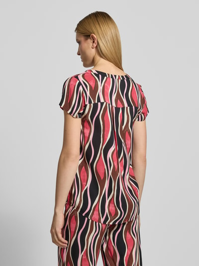 Vrouwenmodel draagt Regular Fit T-shirt uit zuiver viscose model 'Cammi' van Soyaconcept met tuniekhals, ruglengte maat S 69 cm, mouwlengte 15 cm, roze en bruine golvende patronen, gladde stof, volledige rugaanzicht.