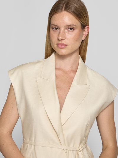 Frauenmodel trägt Weste mit Reverskragen von Jake*s Cocktail aus Reine Baumwolle, Tailliertes Ärmelloses-Design, Paspeltaschen, Nahaufnahme Oberkörper.