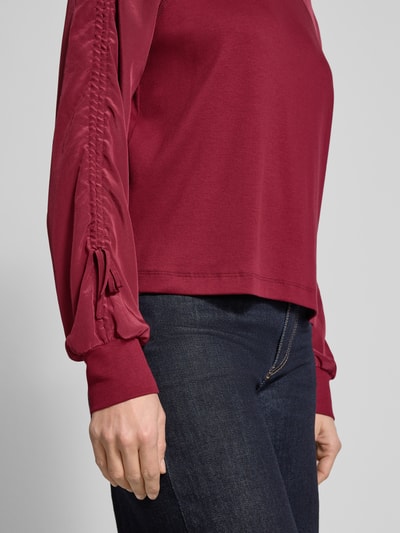Frauenmodel trägt Relaxed Fit Longsleeve mit Raffungen von Marc Cain in Dunkelrot, elastischer Baumwoll-Mix, Nahaufnahme Oberkörper.