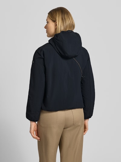 Vrouwenmodel draagt zwarte dames jack met capuchon, labeldetail, regular fit, korte ruglengte, model 'SHELLY2' van khujo, geheel achteraanzicht.