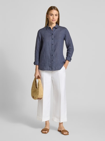 Frauenmodel trägt Leinenbluse mit Label-Detail und Hemdblusenkragen von Fynch-Hatton in Dunkelblau zu weißer Hose, Ganzkörperansicht von vorne. Reines Leinen, Regular Fit, Knopfleiste, abgerundeter Saum, strukturierte Oberfläche.