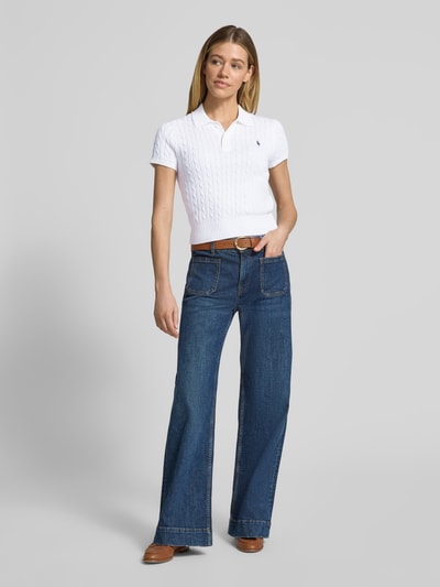 Frauenmodel trägt Regular Fit Strick-Poloshirt aus reiner Baumwolle von Polo Ralph Lauren in Optik: Unifarben, Zopfmuster, Label-Stitching, Polokragen, Kurzarm, Ärmelabschluss: gerippt, Rumpfabschluss: gerippt, Materialverarbeitung: Strick, Material: reine Baumwolle, Ganzkörperansicht von vorne.