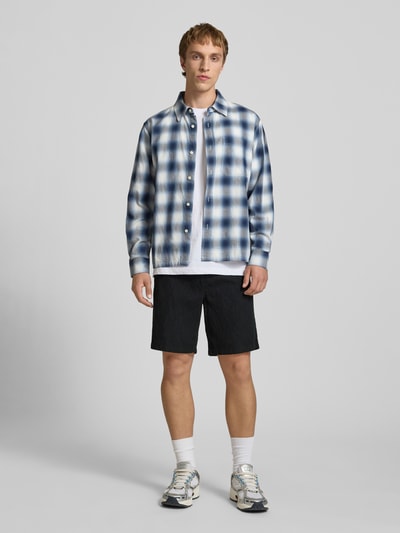 Männermodel trägt Shorts mit Strukturmuster Modell 'JAIDEN' von Jack & Jones, Regular-Fit, Material-Mix mit Baumwoll-Anteil, dunkle Farbe, Ganzkörperansicht von vorne.