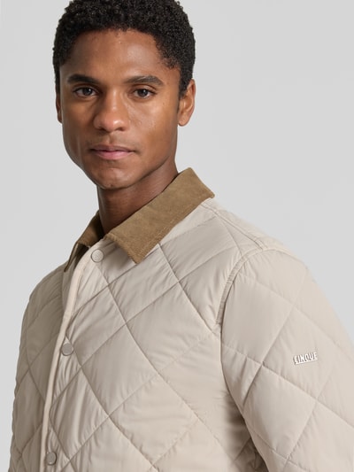 Männermodel trägt Regular Fit Jacke in Stepp-Optik Modell 'Rapid' von CINQUE in Beige mit Umlegekragen, Nahaufnahme Oberkörper. Elastischer Material-Mix, aufgesetzte Taschen und durchgängige Knopfleiste, Rückenlänge 73 cm, Schulterbreite 45 cm, Brustweite 56 cm, Ärmellänge 67 cm.