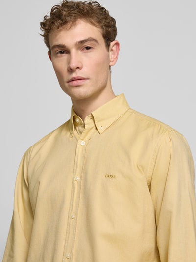 Männermodel trägt Regular Fit Freizeithemd aus reiner Baumwolle Modell 'Rickert' von BOSS Orange in Gelb, Nahaufnahme Oberkörper.
