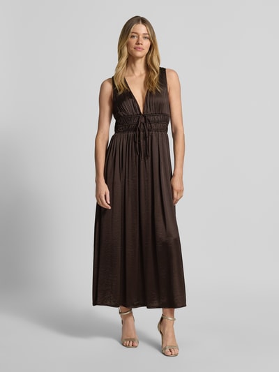 Frauenmodel trägt Maxikleid mit tiefem V-Ausschnitt Modell 'Marja' von mbyM, Material-Mix mit Viskose-Anteil, taillierter Schnitt, Schnürung, dunkelbraune Farbe, glatte Textur, Ganzkörperansicht von vorne.