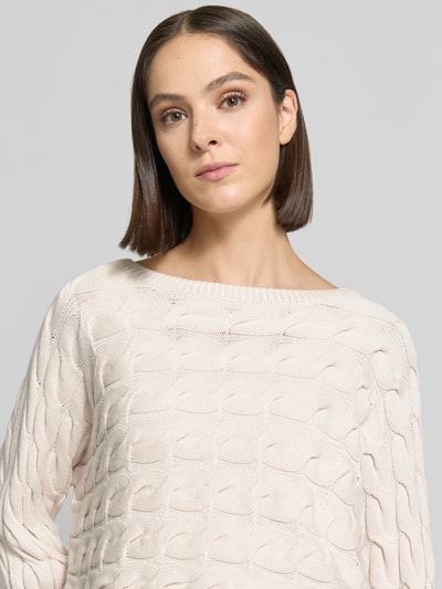 Frauenmodel trägt Relaxed Fit Strickpullover aus Baumwoll-Mix mit Zopfmuster von Oui in Creme, U-Boot-Ausschnitt, Nahaufnahme Oberkörper.
