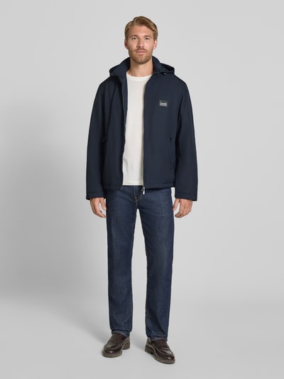 Männermodel trägt Regular Fit Jacke mit Stehkragen von Emporio Armani in Dunkelblau, Logo-Applikation, Zweiwege-Reißverschluss, Eingrifftaschen, Ganzkörperansicht von vorne.