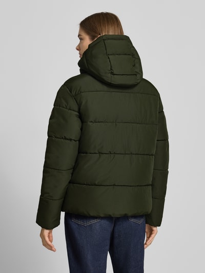 Vrouwenmodel draagt Regular Fit jack in stiksels van Superdry in donkergroen, capuchon met opstaande kraag, afdekstrip, ruglengte maat S 64 cm, schouderbreedte maat S 49 cm, borstwijdte maat S 59 cm, mouwlengte maat S 62 cm, doorgestikte structuur, rechte vormen, gladde textuur, volledig zichtbaar, achteraanzicht.