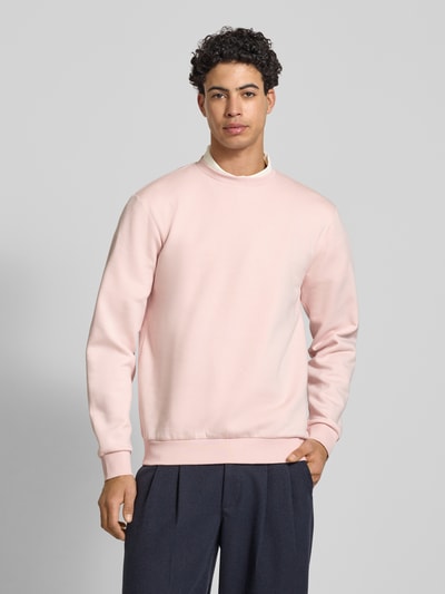 Mannelijk model draagt Regular Fit Sweatshirt aus Baumwoll-Mix Modell 'CERES' van Only & Sons in effen lichtroze, sweatstof, geribde boorden, label patch detail, ronde hals, lange mouwen, ganzebodyvoorzijde.