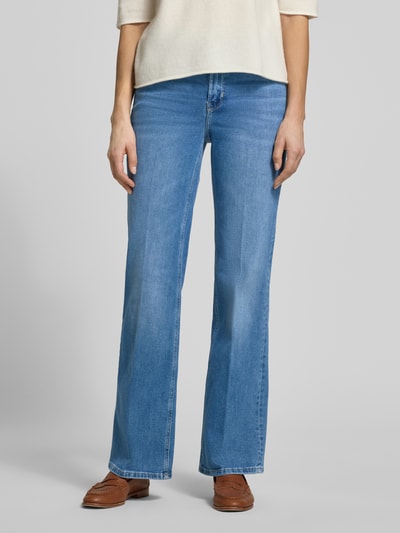 Frauenmodel trägt Straight Fit Jeans mit Gesäßtaschen Modell 'Carie' von Someday aus elastischem Baumwoll-Mix in Mittelblau, Nahaufnahme Oberkörper, Bundweite bei Größe 36: 36 cm, Innenbeinlänge bei Größe 36: 80 cm, Eingrifftaschen, Knopf- und Reißverschluss.