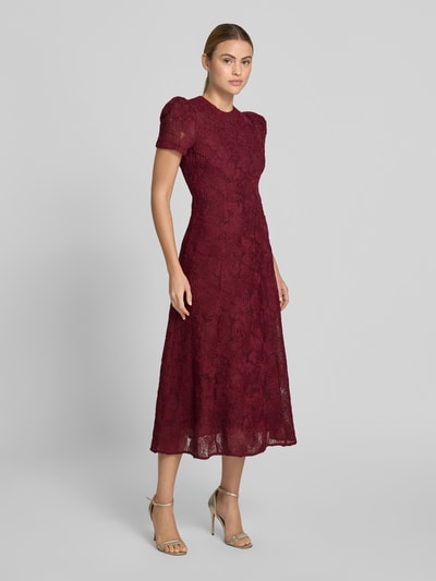 Frauenmodel trägt Maxikleid mit floralem Allover-Besatz von ROTATE aus Elastischer-Material-Mix, taillierte Passform, Rundhalsausschnitt, kurzärmelig, Gesamtlänge 133 cm, Brustweite 45 cm, Ärmellänge 22 cm, Ganzkörperansicht von vorne.