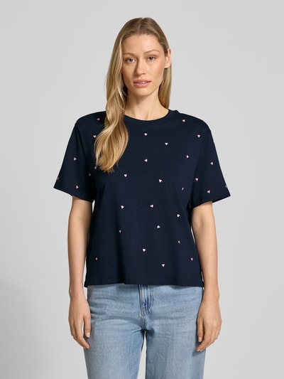 Frauenmodel trägt Boxy Fit T-Shirt aus reiner Baumwolle von Tom Tailor Denim in Dunkelblau mit Allover-Herz-Stickerei, Ganzkörperansicht von vorne.