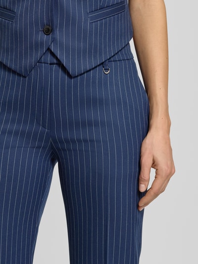 Frauenmodel trägt Regular Fit Anzughose mit Viskose-Anteil Modell 'HILANDO' von HUGO, blau mit feinen weißen Streifen, Nahaufnahme Oberkörper, unifarbene Optik, seitliche Eingrifftaschen, Gürtelschlaufen, Schiebehakenverschluss.