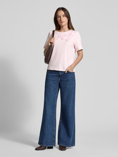 Frauenmodel trägt Regular Fit T-Shirt mit floralem Besatz von Christian Berg Woman Selection, hellrosa, elastischer Baumwoll-Mix, Jeans, Ganzkörperansicht von vorne.