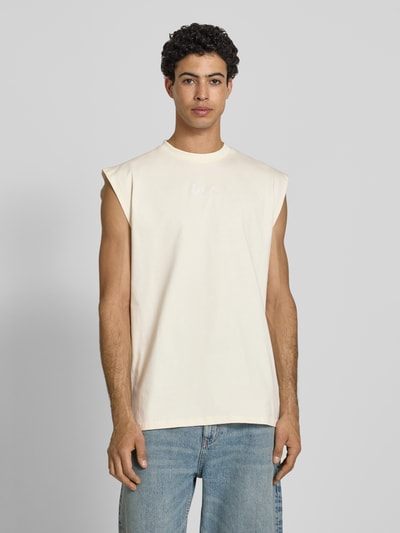 Männermodel trägt T-Shirt mit Label-Stitching von KARL KANI in Beige, Reine Baumwolle, Relaxed-Fit, Rundhalsausschnitt, Ganzkörperansicht von vorne. Rückenlänge bei Größe M 74 cm.