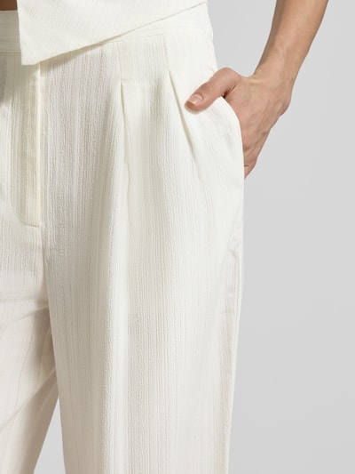 Frauenmodel trägt Hose aus Viskose-Mix mit Strukturmuster von Little Mistress in Creme mit eingewebter Textur, Nahaufnahme Oberkörper.