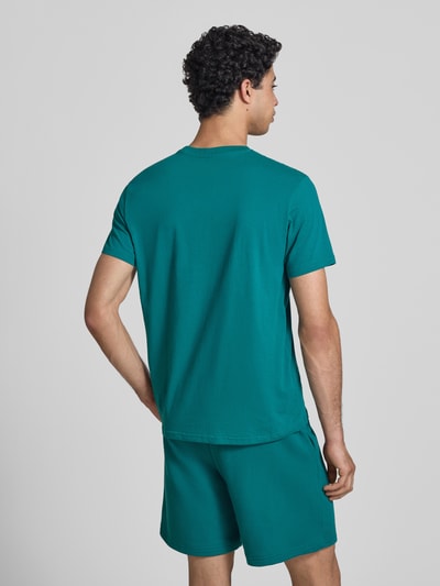 Männermodel trägt T-Shirt mit Label-Print und Rundhalsausschnitt von CHAMPION in Türkis, reine Baumwolle, Regular Fit, Ganzkörperansicht Rückansicht.