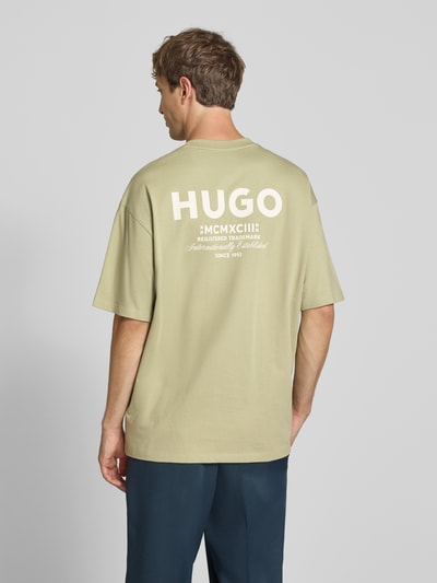 Männermodel trägt Oversized T-Shirts aus reiner Baumwolle Modell 'Nalono' von HUGO Blue in hellem Grün, Ganzkörperansicht Rückansicht.