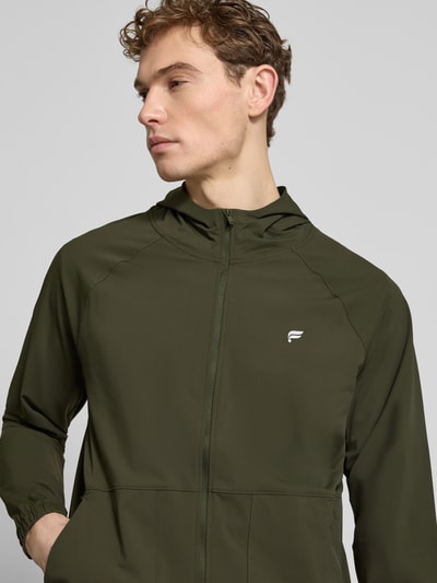 Männermodel trägt Herren Jacke von Fabletics, Regular-Fit, Elastischer-Material-Mix, Kapuze, Reißverschluss, Logo-Print, Nahaufnahme Oberkörper
