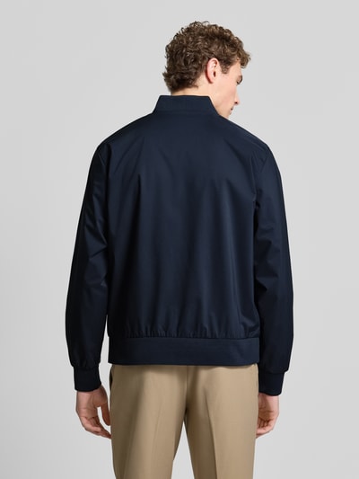 Männermodel trägt dunkelblaue Bomberjacke mit Stehkragen und Reißverschlusstaschen, Modell 'MATTE' von CK Calvin Klein, Ganzkörperansicht Rückansicht.