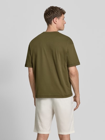 Männermodel trägt Regular Fit T-Shirt aus reiner Baumwolle von Tommy Hilfiger in Olivgrün, unifarben, kurzarm, Jersey. Ganzkörperansicht Rückansicht.