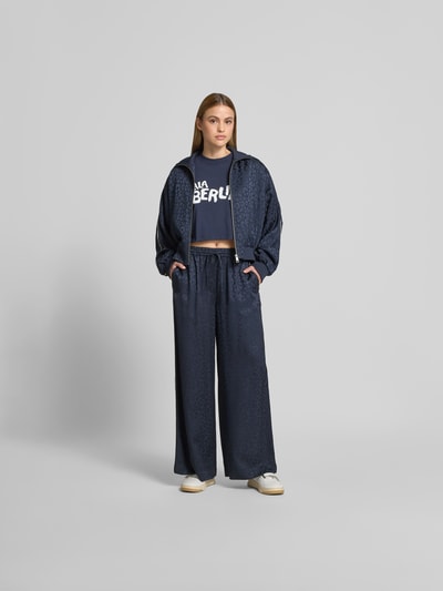 Frauenmodel trägt Wide Fit Sweatpants mit Viskose-Anteil von Lala Berlin, dunkelblau mit Animal-Print, elastischer Bund, Ganzkörperansicht von vorne.