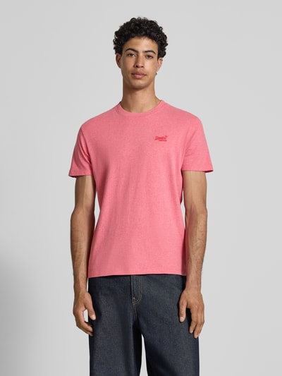Männermodel trägt Regular Fit T-Shirt mit Logo-Stitching von Superdry in Rosa, reine Baumwolle, Rundhalsausschnitt, Ganzkörperansicht von vorne.