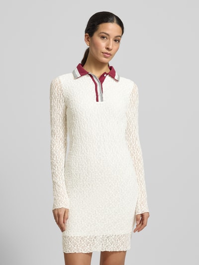 Frauenmodel trägt Slim Fit Kleid mit Polokragen von Marc Cain, Spitzenstruktur, weiß, langärmelig, semitransparent, Nahaufnahme Oberkörper.