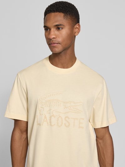 Männermodel trägt Regular Fit T-Shirt aus reiner Baumwolle von Lacoste in Optik: Unifarben, Logo-Print, Rundhals, Kurzarm, Nahaufnahme Oberkörper.