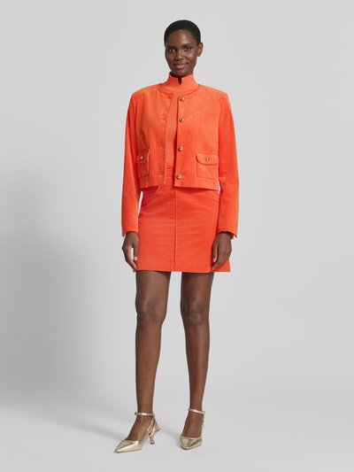 Frauenmodel trägt Regular Fit Kurzblazer aus reiner Baumwolle von Marc Cain in kräftigem Orange, Cordstruktur, Knopfleiste, Pattentaschen, Rundhalsausschnitt, Ganzkörperansicht von vorne.