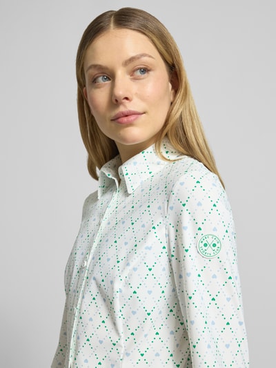 Frauenmodel trägt Slim Fit Bluse im Allover-Look von Marc Cain, weiß mit grünem Muster, Material-Mix mit Stretch-Anteil, Nahaufnahme Oberkörper.
