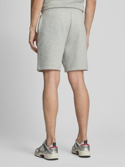 Männermodel trägt Sweatshorts mit elastischem Bund von GAP in Hellgrau, Baumwoll-Mix, Relaxed-Fit, Logo, Ganzkörperansicht Rückansicht.