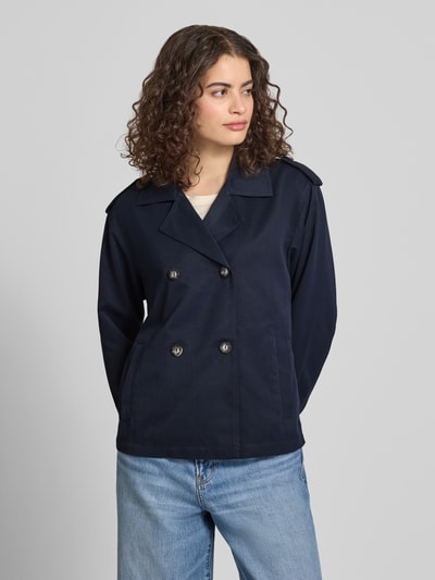 Frauenmodel trägt Regular Fit Trenchcoat-Jacke mit Reverskragen Modell 'HANNAH' von Only in Optik: Unifarben, Ganzkörperansicht von vorne. Passform: Regular-Fit, Verschluss: doppelreihige Knopfleiste, Applikation: Schulterriegel, Details: Rückenpasse, Ärmelform: Langarm, seitliche Eingrifftaschen.