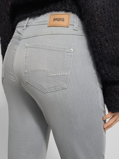 Kobiece model prezentuje Jeansy z wpuszczanymi kieszeniami Model 'Ornella' od Angels, mieszanka bawełny z dodatkiem streczu, krój slim fit, wpuszczane kieszenie, szerokość w rozmiarze 36: 40 cm, długość wewnętrzna nogawki w rozmiarze 36: 67 cm, szara tkanina o gładkiej teksturze, detalowa linia kieszeni. Detailaufnahme tył.