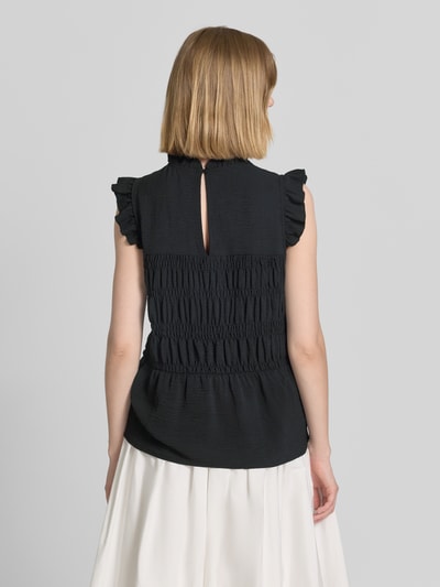 Frauenmodel trägt Blusentop mit Rüschenkragen Modell 'CATH' von Soyaconcept, Körpernaher-Schnitt, Rüschenärmel, Smok-Detail, schwarze Struktur, Rückenlänge 60 cm bei Größe S, Ärmel 5 cm, Ganzkörperansicht Rückansicht.