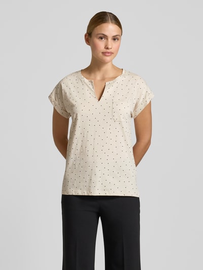 Vrouwenmodel draagt T-Shirt met borstzakje model 'Viva' van FREE/QUENT, effen beige met zwarte stippen, rechte fit, serafino hals, korte mouw met vaste omslag, zuiver katoen, vooraanzicht hele lichaam.