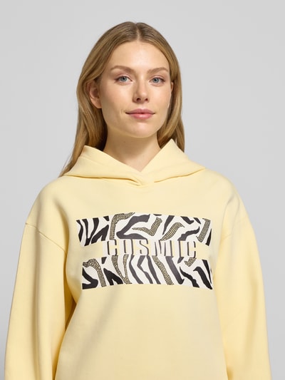 Frauenmodel trägt Hoodie mit Kapuze von Marc Cain, Reine Baumwolle, Lockerer-Schnitt, Label-Print, Gerippte-Abschlüsse, Nahaufnahme Oberkörper.