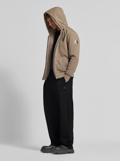Männermodel trägt schwarze Sweatpants mit elastischem Bund von Moose Knuckles aus Baumwollmischung, gerader Schnitt, Nahaufnahme Oberkörper.