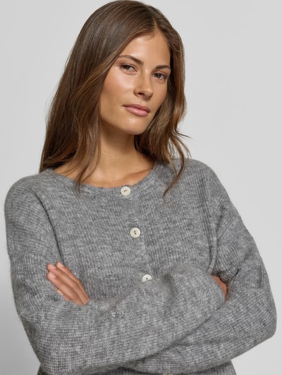 Vrouwenmodel draagt gebreid jack met wol van MYON in grijs, riblook, doorlopende knoopsluiting, ronde hals, elastische materiaalmix, recht pasvorm, dames, nahaufnahme bovenlichaam.
