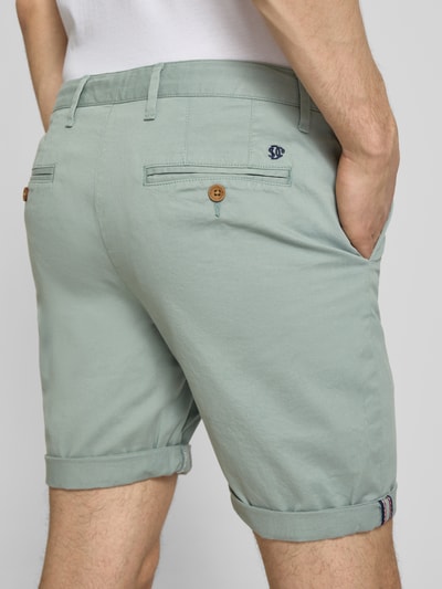 Männermodel trägt Regular Fit Shorts mit Münztasche von Superdry in Mintgrün, Baumwoll-Mix, Gesäßtaschen, Knopf-Reißverschluss, Ganzkörperansicht Rückansicht.