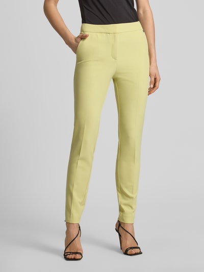 Vrouwenmodel draagt Slim Fit Schmale Hose met LOGO-Niete model 'HAGONIA-1' van HUGO, look: effen, mid rise, stretch materiaalverwerking, steekzakken, persplooien, zacht geel, kleurrijk, riemlussen, sluiting met haak en verborgen ritssluiting, vooraanzicht volledige lichaamsopname.