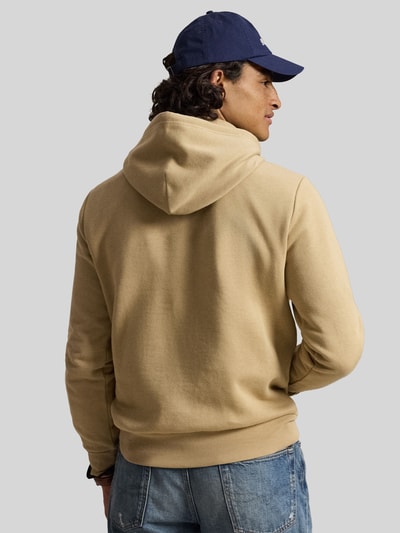 Männermodel trägt beigen Relaxed Fit Hoodie aus Baumwoll-Mix von Polo Ralph Lauren, Struktur weich, Ganzkörperansicht Rückansicht.