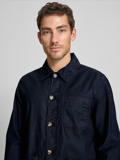 Männermodel trägt Regular Fit Hemdjacke aus Leinen-Mix von Gant in Dunkelblau, Umlegekragen, Knopfleiste, Aufgesetzte Taschen, Nahaufnahme Oberkörper.
