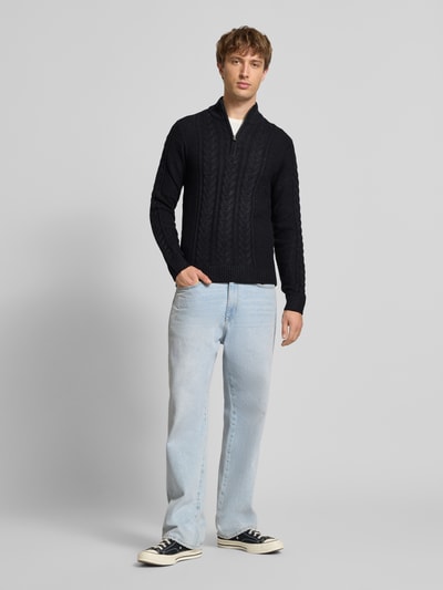 Męski model nosi Sweter z dzianiny z mieszanka bawełny, krój slim fit, ścieg warkoczowy, stójka, zamek błyskawiczny, detal z logo, Model 'BASIM' od Blend, długość tyłu 73 cm, długość rękawów 72 cm, widok całej sylwetki od przodu